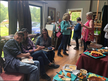 group of artists casually dressed standing and talking in an art studio eating snacks